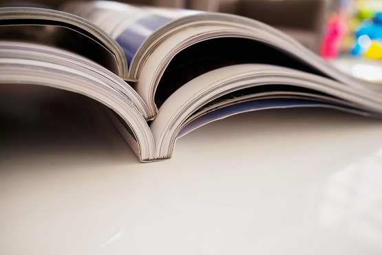 Pile of magazines stack on white table in living room close up